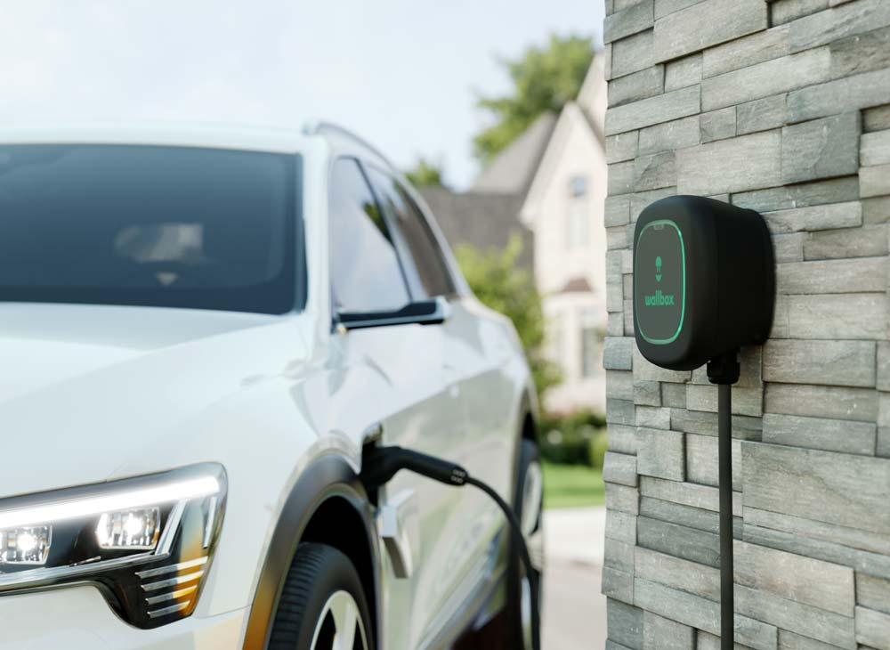 electric car plugged in to a home EV charger mounted to wall