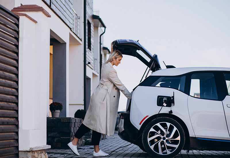 blonde female unloading trunk while charging an EV